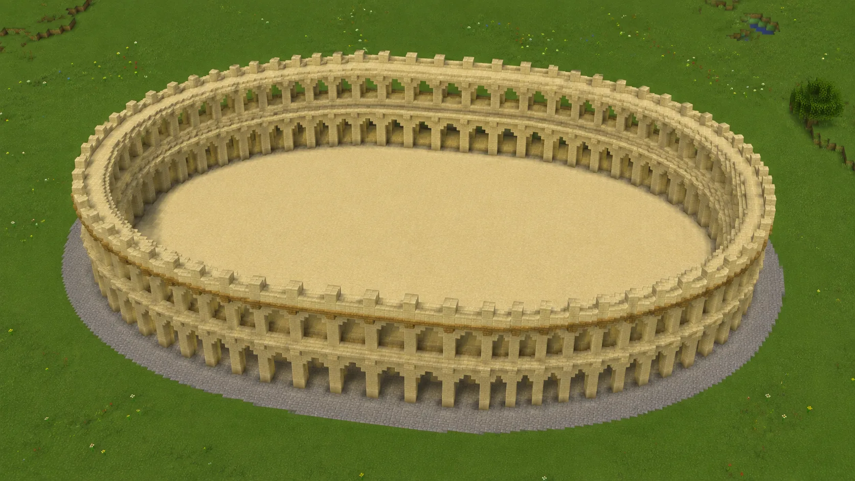 A Minecraft colosseum from above, two tiers of sandstone arches enclosing an oval sand arena floor